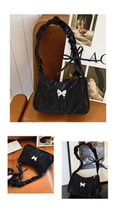 Macro shot of black pleated fabric and elegant white butterfly detail on shoulder bag