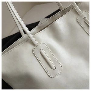 Detail of white leather tote bag showing reinforced stitching and premium matte texture