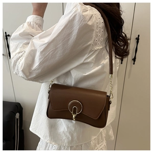 Detailed shot of brown shoulder bag with a round gold buckle and chain strap