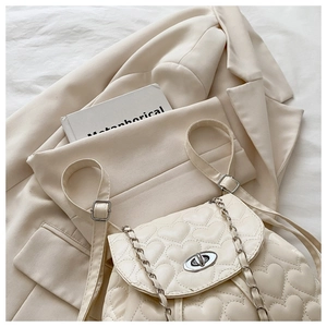 Detail of cream white quilted backpack with heart pattern stitching and silver chain