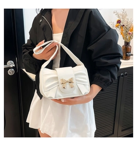 Detail of white pleated handbag with golden bow accent and elegant tiered texture