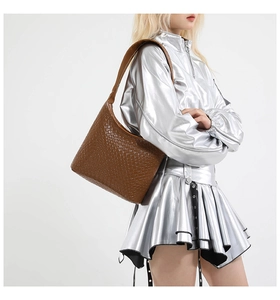 Close-up of brown woven texture shoulder bag worn with a stylish silver metallic outfit