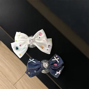 Detail of rhinestone bow phone socket in white satin and blue denim fabric