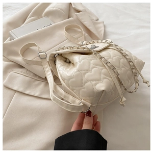 Close-up of heart-quilted leather texture and silver chain drawstring on a chic backpack