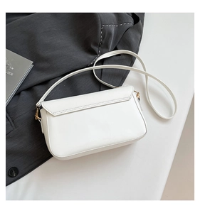Detail of white PU leather crossbody bag with gold hardware on a grey blazer
