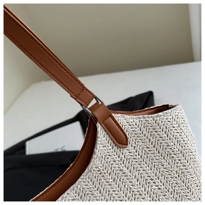 Detailed close-up of woven herringbone straw tote bag with brown faux leather shoulder strap