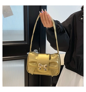 Detail of champagne gold bow handbag with a metallic lock and chain strap