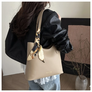 Detail of beige PU leather tote bag with printed silk scarf on strap for stylish women