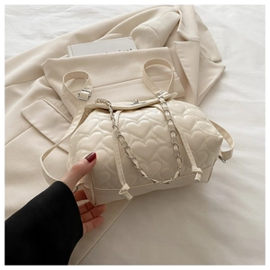 Detail of cream backpack featuring heart quilted stitching and metal chain straps