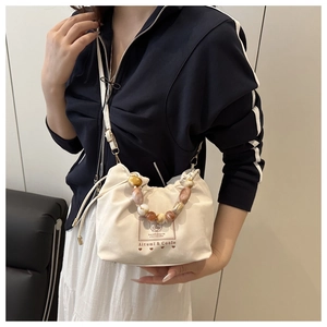 Détail du sac beige avec anse en perles ambrées dégradées et logo Aitumi & Coole
