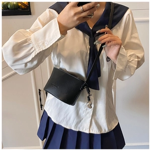 Detail of black pebbled crossbody bag with silver heart pendant on a JK uniform style