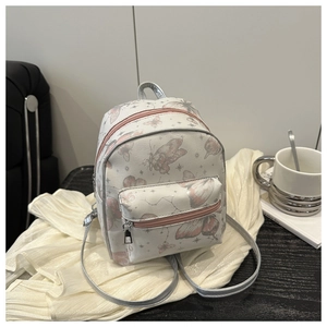 Close-up of mini white backpack with pink butterfly prints and silver shoulder straps