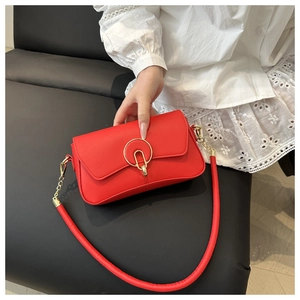 Vue détaillée d'un sac à bandoulière rouge vif avec une boucle dorée et un anneau métallique