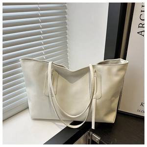 Detailed close-up of a minimalist white matte leather tote bag in a stylish indoor setting