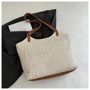 Close-up of woven straw tote bag with brown PU leather base on a black blazer