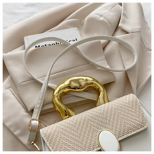 Close-up of cream woven handbag featuring a unique irregular gold metal top handle