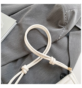 Detail of ivory shoulder bag showing knotted leather strap and gold metal hardware caps