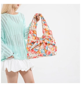 Detailed view of the 3D floral tote bag with a large bow held by a model in casual attire