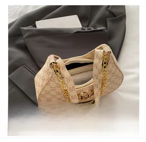 Macro shot of beige dumpling bag featuring monogram M pattern and gold chain hardware