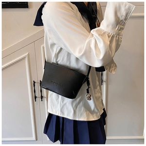 Detail of black lychee texture bucket bag with delicate heart pendant and slim shoulder strap