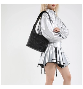 Detail of black woven texture on minimalist tote bag worn by model in silver outfit