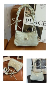 Close-up of sage green pleated handbag featuring silver butterfly and knotted strap detail