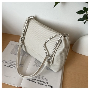 Detail of minimalist beige canvas bag featuring woven texture and gold chain strap
