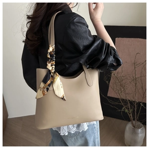 Close-up of beige leather tote bag with a decorative vintage patterned silk scarf on strap