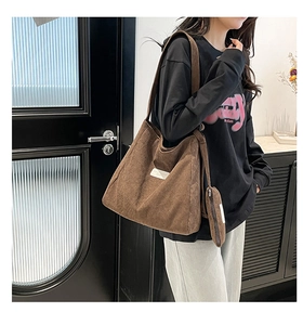 Detail of dark brown corduroy tote bag showing striped texture and small zipper coin purse
