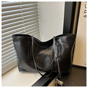 Close-up of black leather tote bag with glossy finish and reinforced shoulder strap stitching