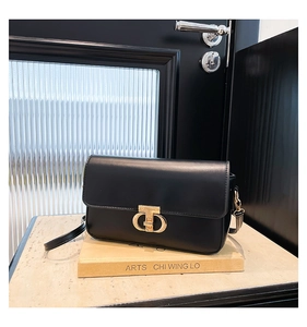 Detail shot of black PU leather shoulder bag featuring a gold metal twist lock buckle