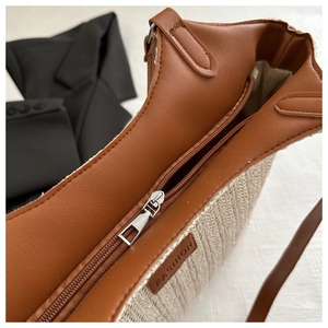 Detail of woven straw bag with leather trim, metal zipper and interior lining view