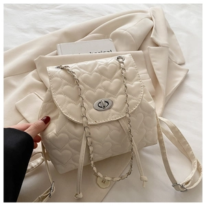 Close-up of heart-shaped quilted pattern and silver clasp on a cream chain backpack