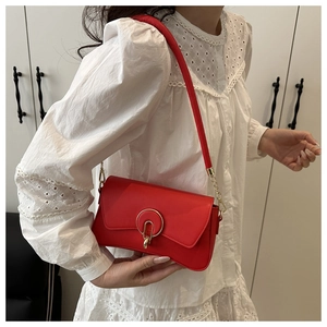 Close-up of red leather shoulder bag featuring a stylish gold ring buckle detail