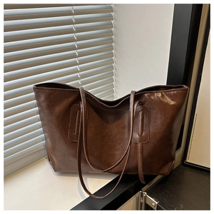 Detail of dark brown tote bag with high-gloss leather texture and reinforced stitching