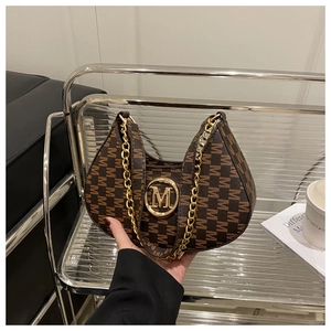 Detailed view of dark brown crescent bag featuring gold M logo and chain strap