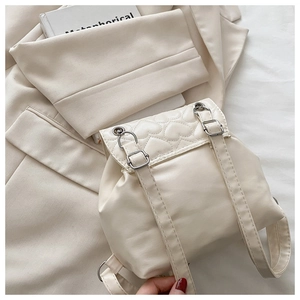 Close-up of heart-shaped quilting and silver buckle on a cream white PU leather backpack