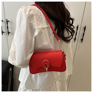 Detail of red matte leather shoulder bag with gold ring buckle and chain strap shown on model
