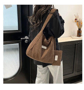 Detailed texture of brown corduroy tote bag showing the branded tag and matching small pouch