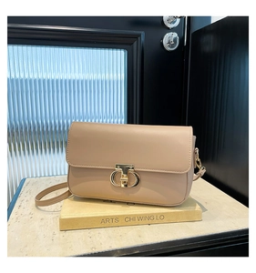 Detailed close-up of a beige PU shoulder bag with round gold metal buckle on a book