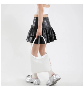 Detail of white woven leather hobo bag styled with black ruffled skirt and silver shoes