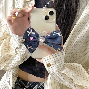 Detail of denim bow phone grip with colorful rhinestones held by hand for a mirror selfie