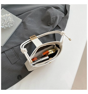 Interior view showing capacity of off-white PU handbag with golden clasp on grey blazer