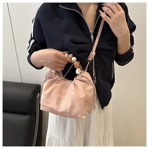 Détail du sac à main rose avec poignée en perles marbrées et cordon de serrage chic