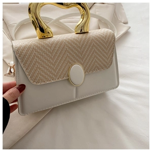 Detail of elegant gold heart-shaped metal handle on cream textured crossbody bag