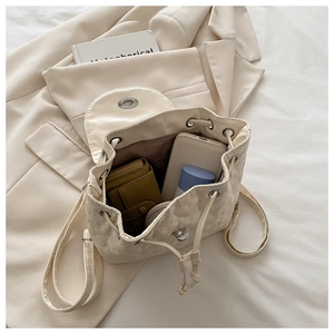 Spacious interior of beige heart-quilted backpack holding phone and cosmetics