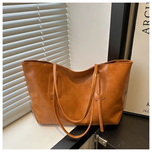 Detail of vintage brown leather tote bag with retro texture and stitched decorative panel