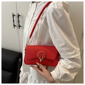 Detail of red faux leather shoulder bag featuring a gold circular hollow metal buckle