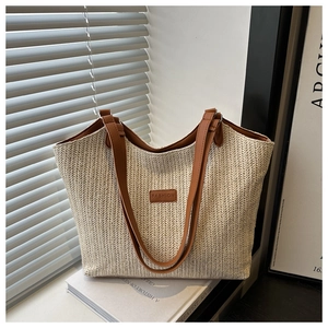 Close-up of woven straw tote bag with brown leather handles and a fashion patch