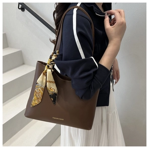 Détail d'un sac cabas marron foncé avec foulard décoratif et lettrage doré